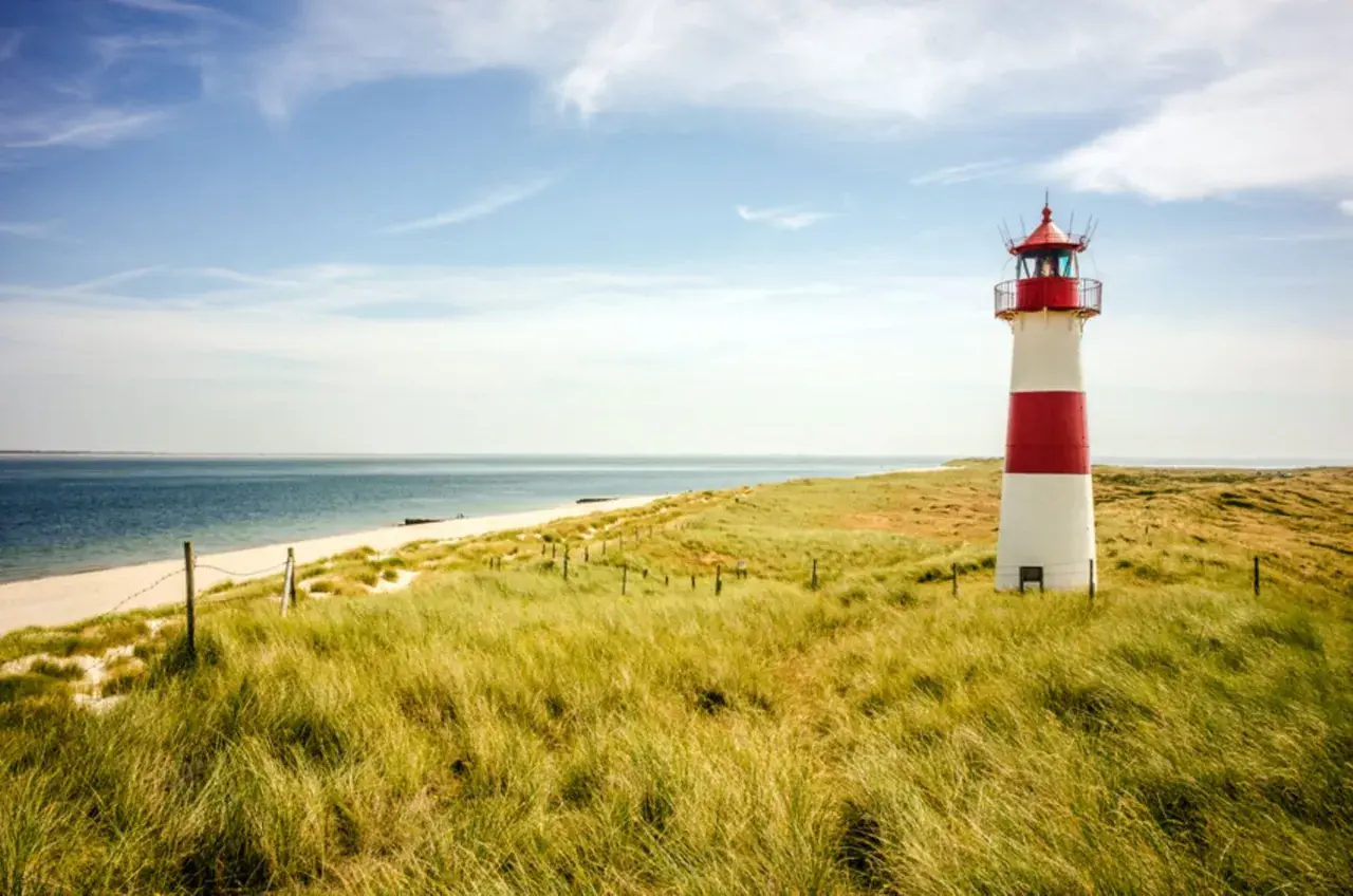 Leuchtturm am Strand mit Dünen, ein **Geheimtipp Urlaub August Deutschland**.