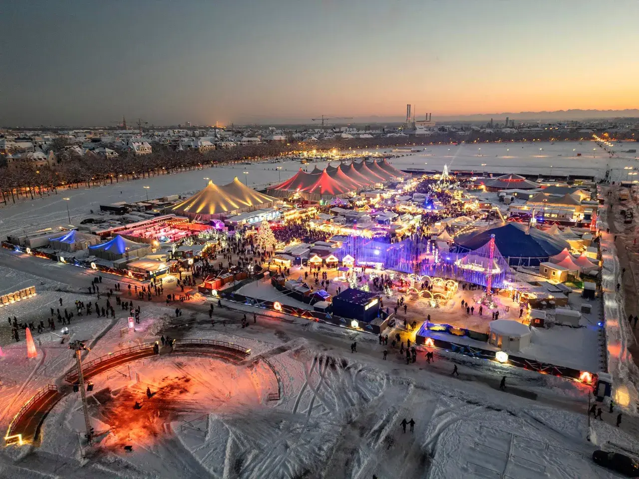 Winterzauber auf dem weihnachtsmarkt theresienwiese. Bunte Lichter, Schnee und Menschenmassen unter Zelten und Lichtern.