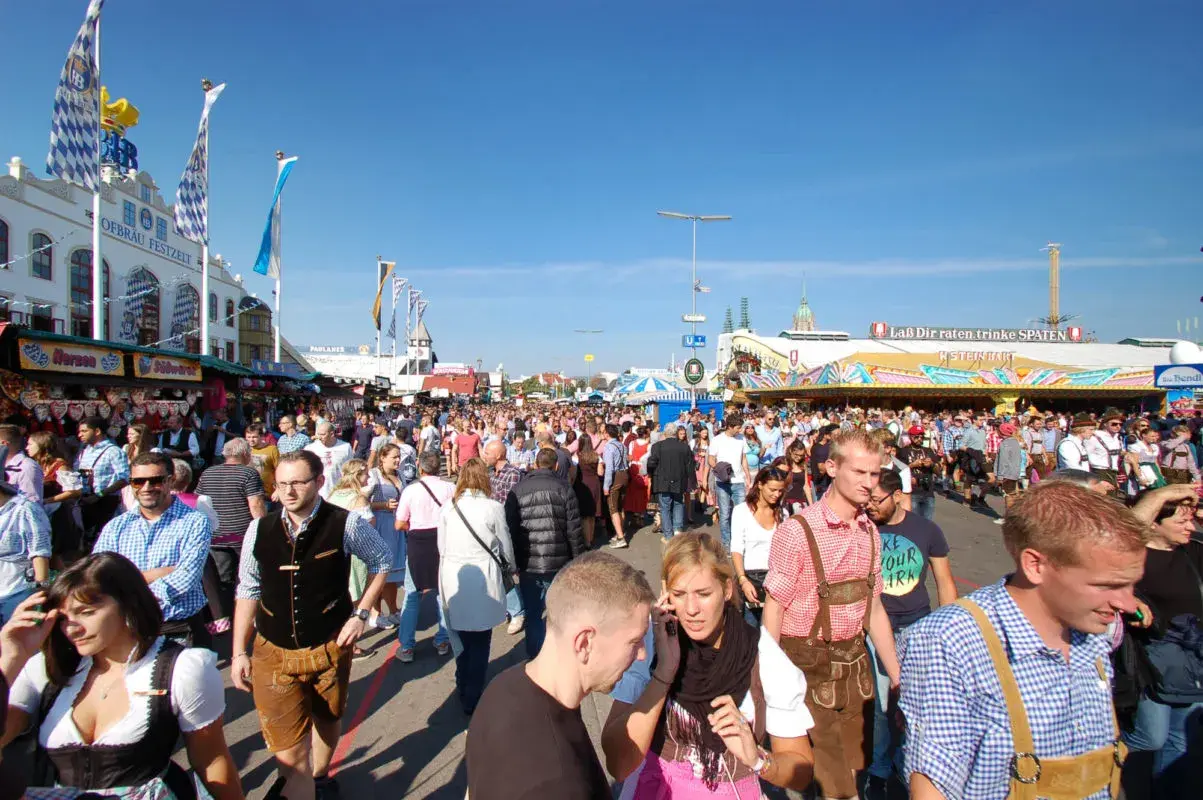 Menschenmassen auf dem Oktoberfest 2026, viele in Tracht, unter blauem Himmel.
