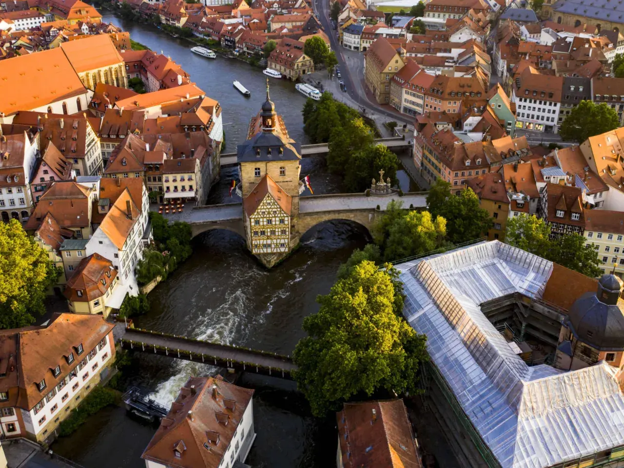 Luftaufnahme von Bamberg: Das Alte Rathaus thront über dem Fluss, umgeben von roten Dächern. Ein perfekter Ort für einen Bamberg Tagesausflug.