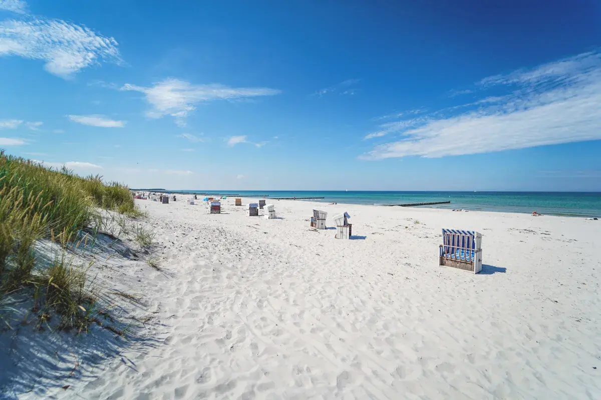 Ein perfekter Hiddensee Urlaub: Weißer Sandstrand, blaue Ostsee und Strandkörbe laden zum Entspannen ein.