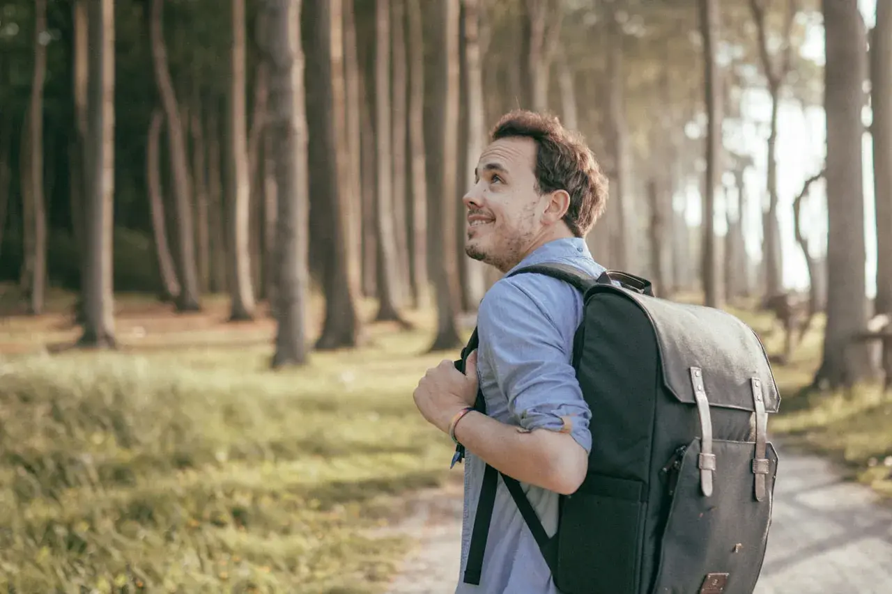 Ein Mann mit Rucksack wandert durch den gespensterwald nienhagen, die Bäume ragen mystisch in den Himmel.