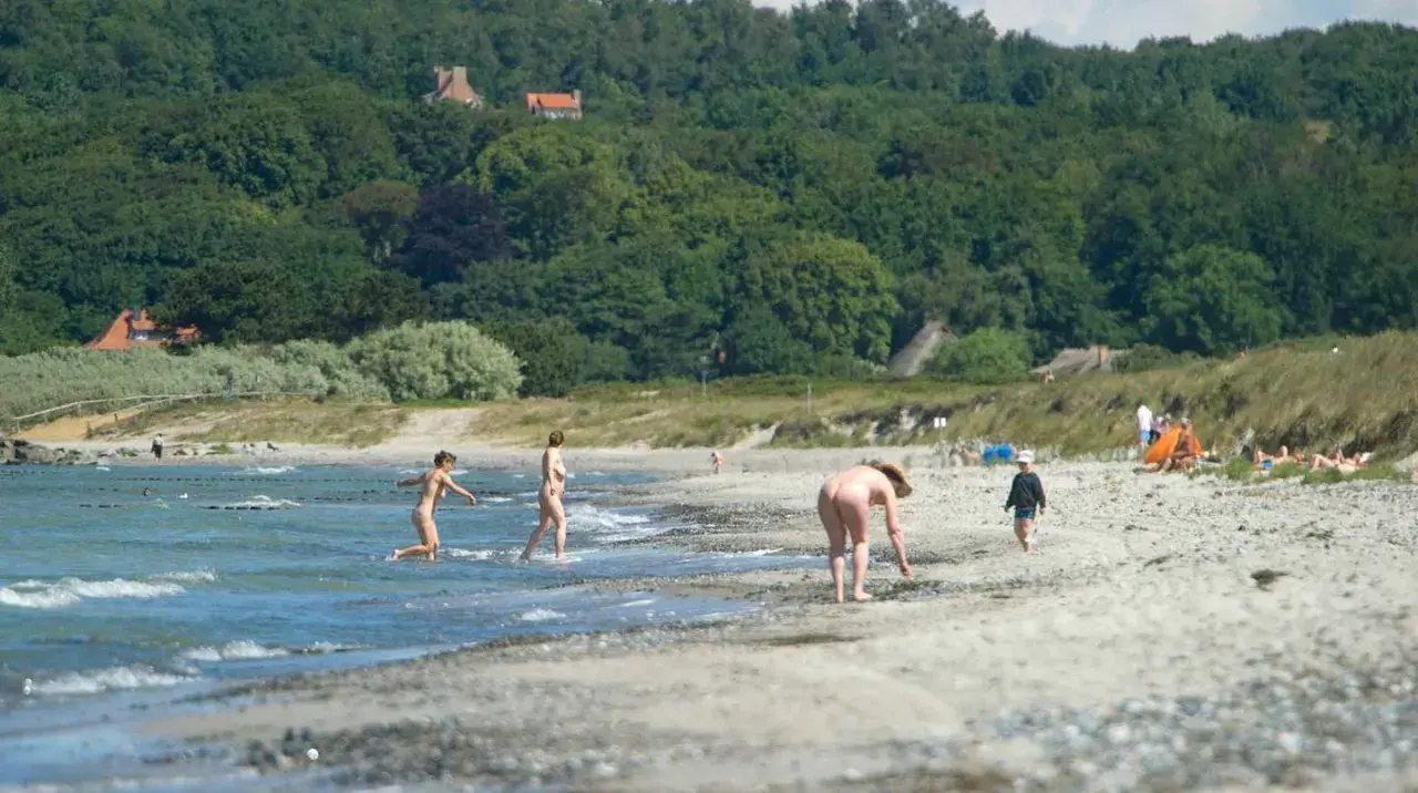 Menschen genießen einen sonnigen Tag am Strand von Hiddensee, einige baden, andere entspannen sich. FKK ist hier erlaubt.