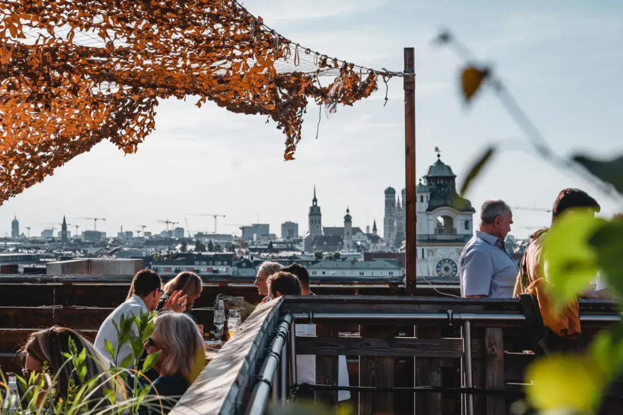 Menschen genie&szlig;en den Ausblick auf den rooftop Munich mit der Frauenkirche im Hintergrund.