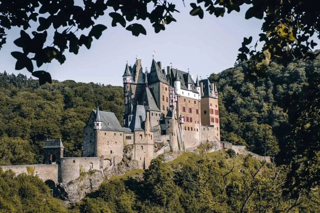 Mächtige Burg Eltz thront auf einem Hügel, umgeben von grünen Wäldern. Ein tolles Ziel für eine Wanderung bei Cochem.