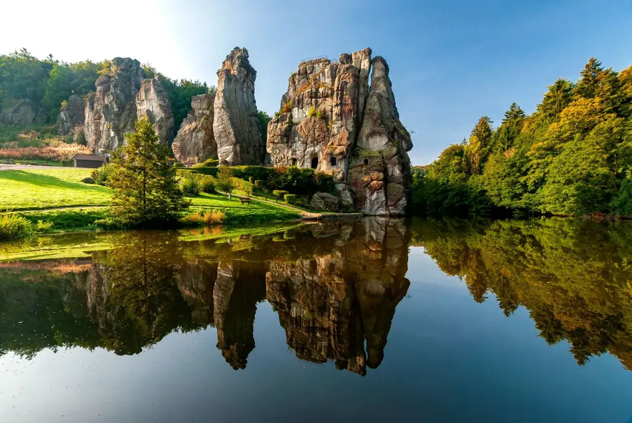 Die Externsteine spiegeln sich in einem ruhigen See. Ein toller Tipp f&uuml;r Deutschland Reisetipps!