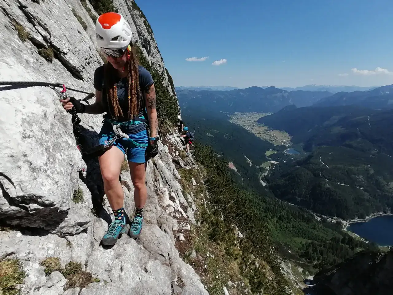 Frau klettert gesichert am Himmelsleiter Klettersteig mit atemberaubendem Blick ins Tal.