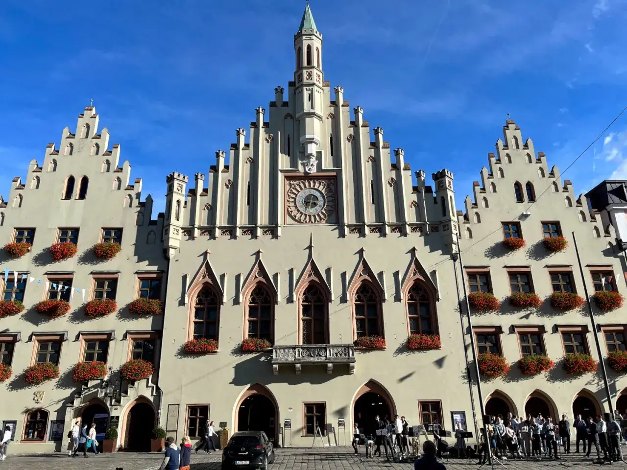 Prachtvolles Rathaus in der Landshut Altstadt mit blumengeschmückten Fenstern und einem Glockenspiel.