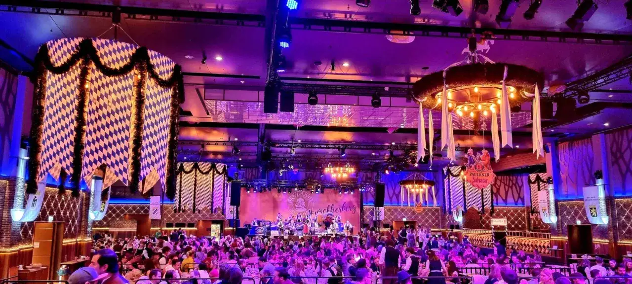 Festliche Stimmung beim Starkbierfest mit bayerischer Deko, Band auf der Bühne und vielen Gästen in Tracht.