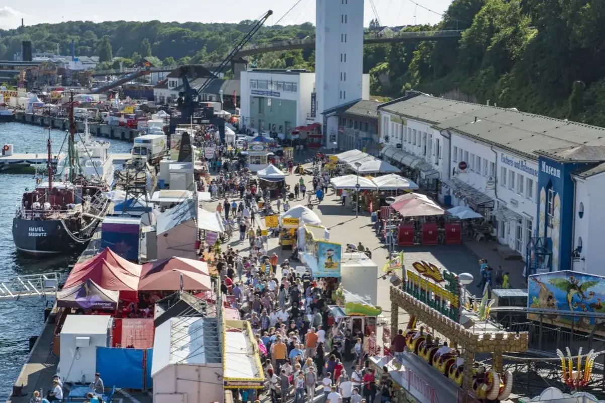 Volles Hafenfest in Sassnitz mit vielen Menschen, Fahrgeschäften und dem Schiff