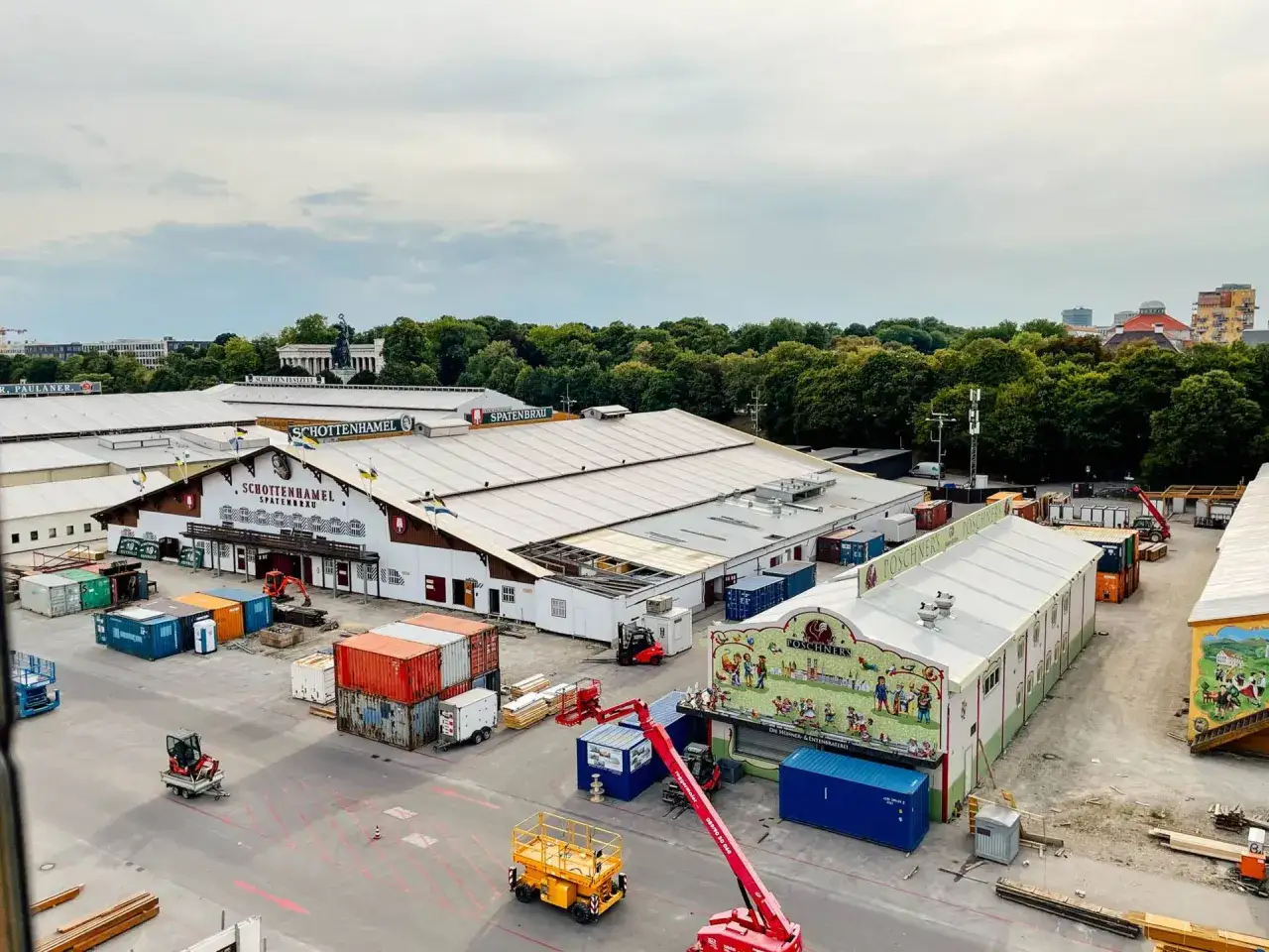 Oktoberfest Aufbau: Zelte und Container werden angeliefert. Kräne und Bagger sind im Einsatz, um alles für das Fest vorzubereiten.