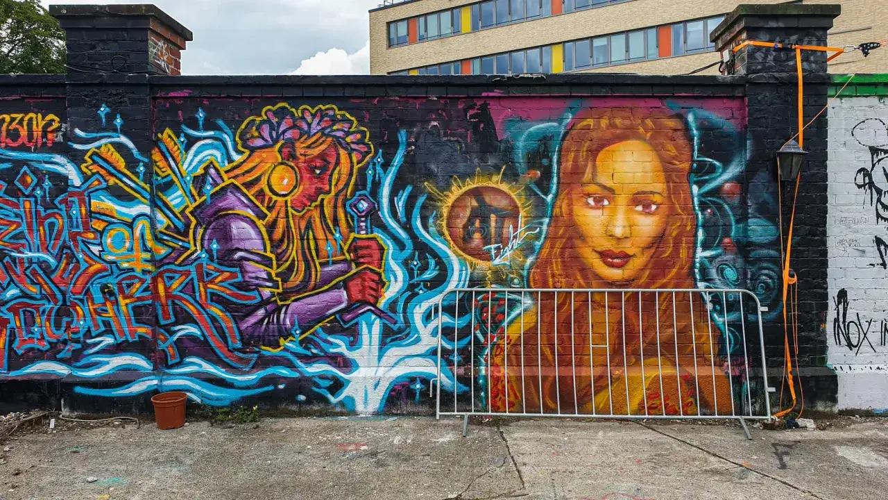 Farbenfrohe Street Art in München: Eine Kriegerin mit Schwert und ein Porträt einer Frau zieren die Mauer.