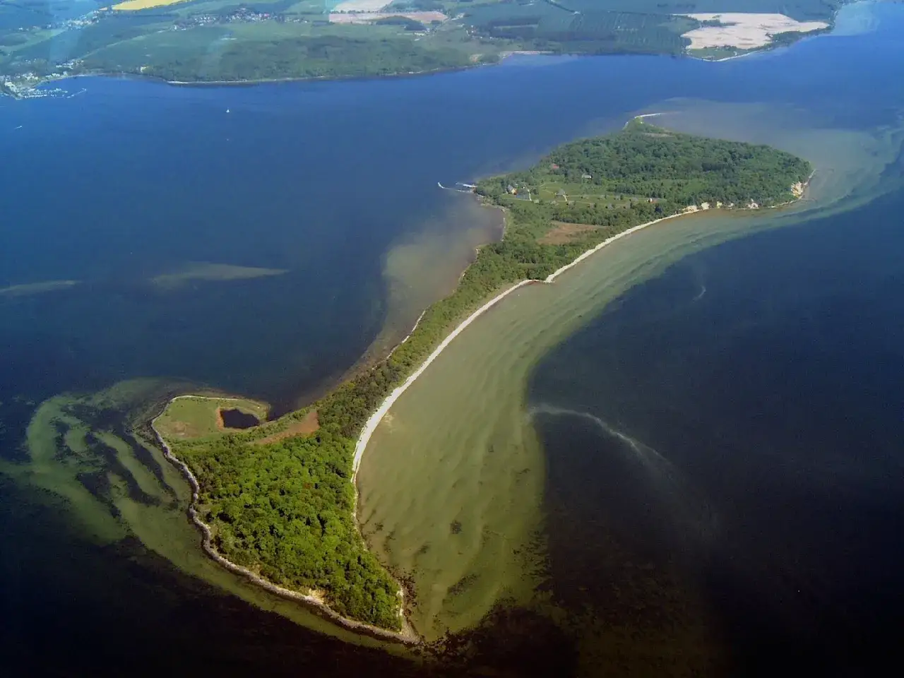 Luftaufnahme der Insel Vilm mit grünen Wäldern, weißen Stränden und türkisfarbenem Wasser.