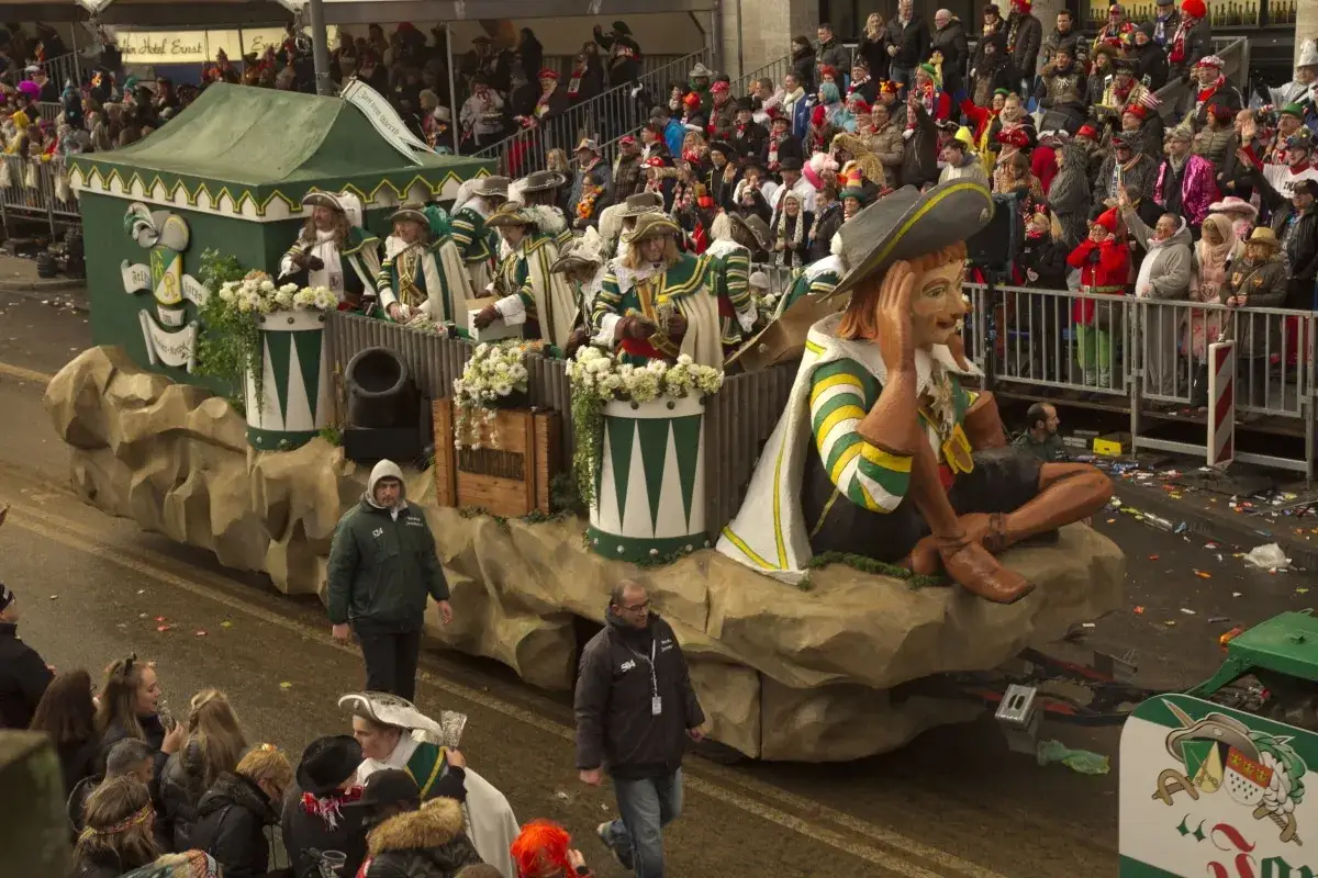 Karnevalswagen mit Figuren und Menschen in Kostümen, die an einem Umzug teilnehmen.