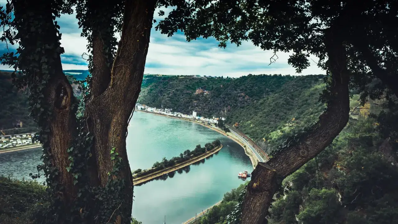Blick auf eine Flusslandschaft mit einer kleinen Stadt und einer Burgruine. Perfekt für Bikepacking Deutschland.