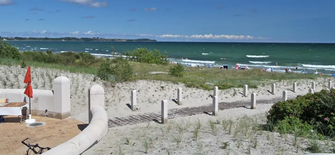 Sonniger Tag am Breege Strand. Menschen genießen das Meer, Strandkörbe und eine kleine Verkaufsbude.