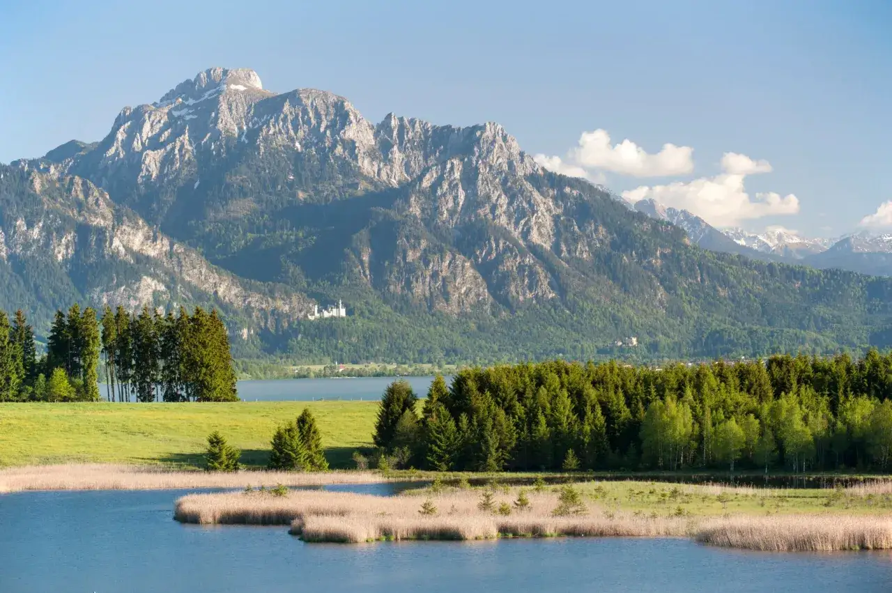 Malerischer Bergsee in Deutschland mit Schloss Neuschwanstein im Hintergrund.