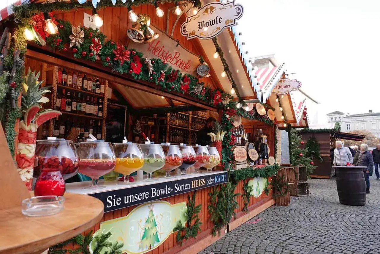 Bunte Bowlen und Glühwein an einem weihnachtsmarkt in Deutschland. Dekoration mit Tannengrün und Lichtern.