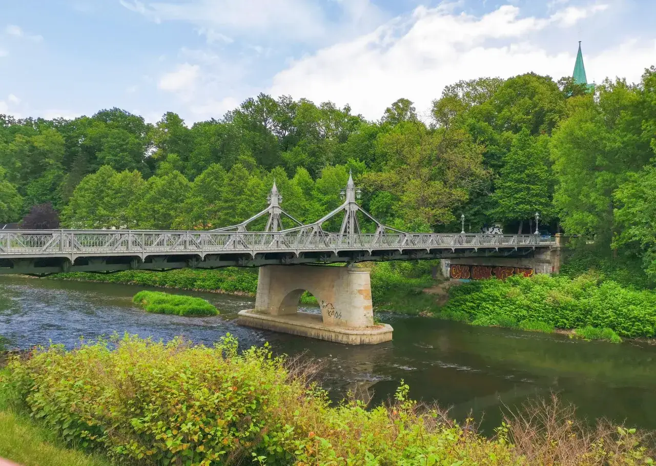 Eine historische Brücke überspannt einen Fluss, umgeben von üppigem Grün. Ein echter Geheimtipp Zwickau für Naturliebhaber.