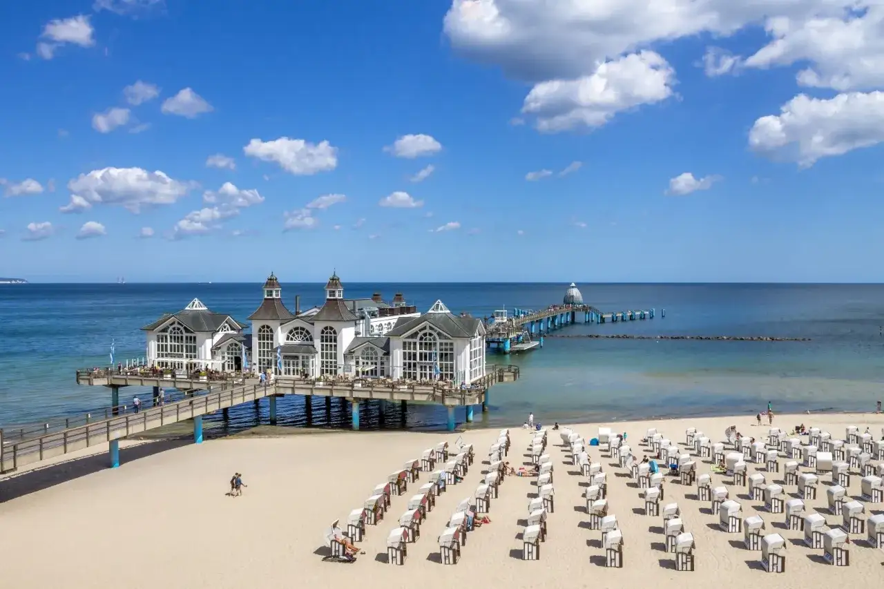 Sellin: weiße Seebrücke mit Bädern, Strandkörbe und blauem Himmel. Entdecken Sie die Geheimtipps von Sellin!