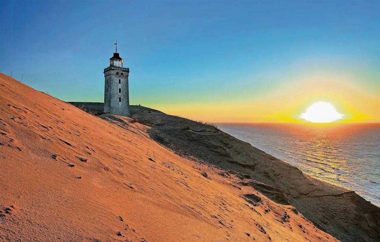 Leuchtturm auf einer Sanddüne bei Sonnenuntergang, wo Nord und Ostsee sich treffen.