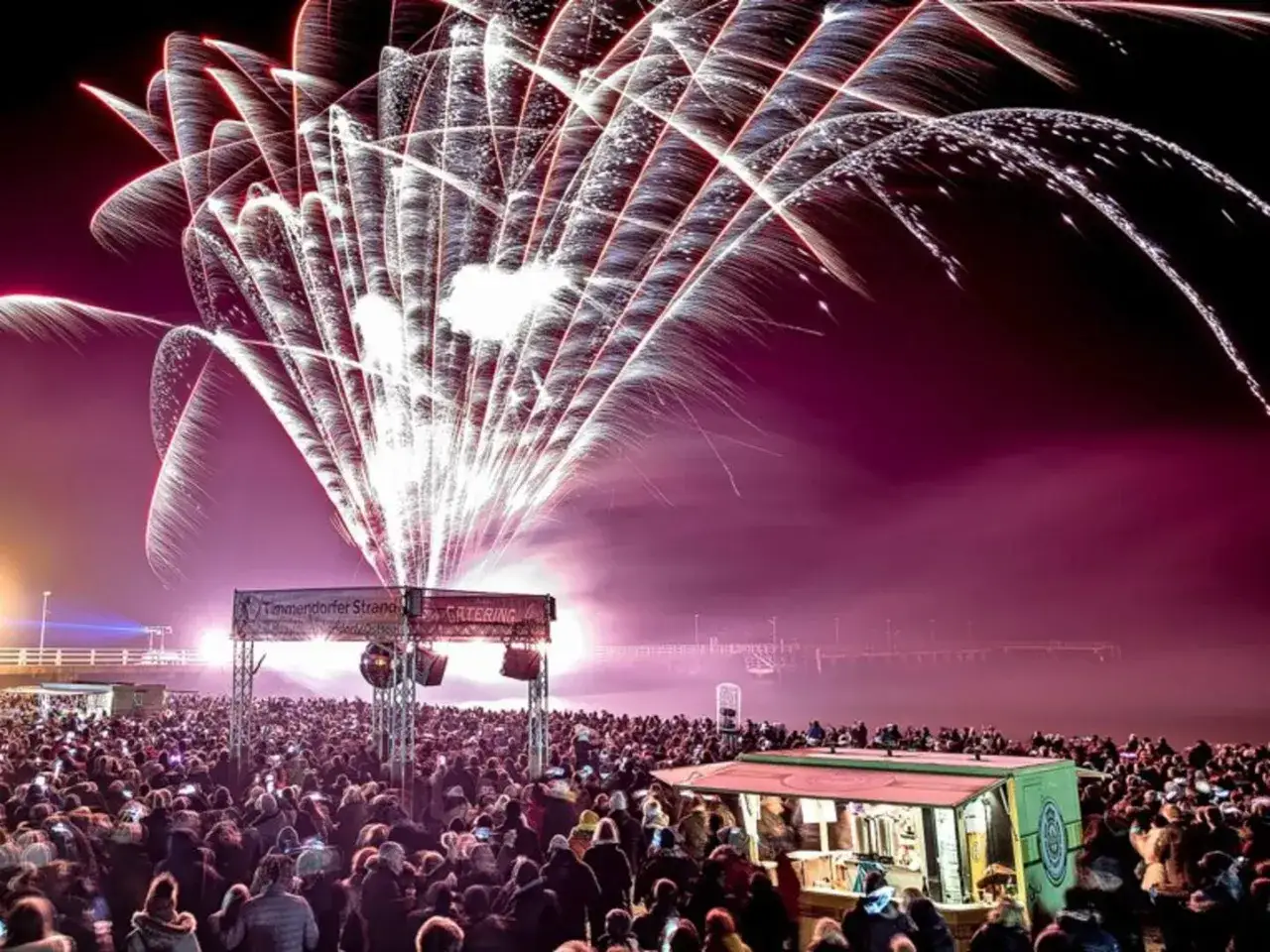 Feuerwerk über einer Menschenmenge am Timmendorfer Strand. Ein unvergesslicher Silvester am Strand mit Lichtern und Jubel.