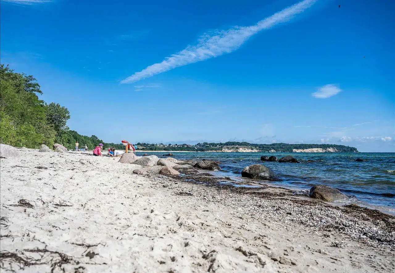 Kinder spielen am lobbe strand. Sand, Steine und das Meer unter blauem Himmel.