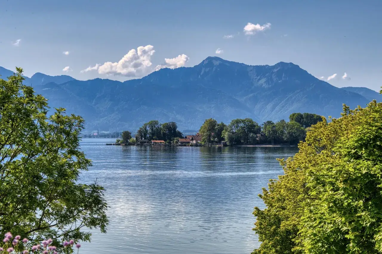 Idyllische Insel mit Häusern und Bäumen am Starnberger See, perfekt für entspanntes Wandern mit Bergblick.